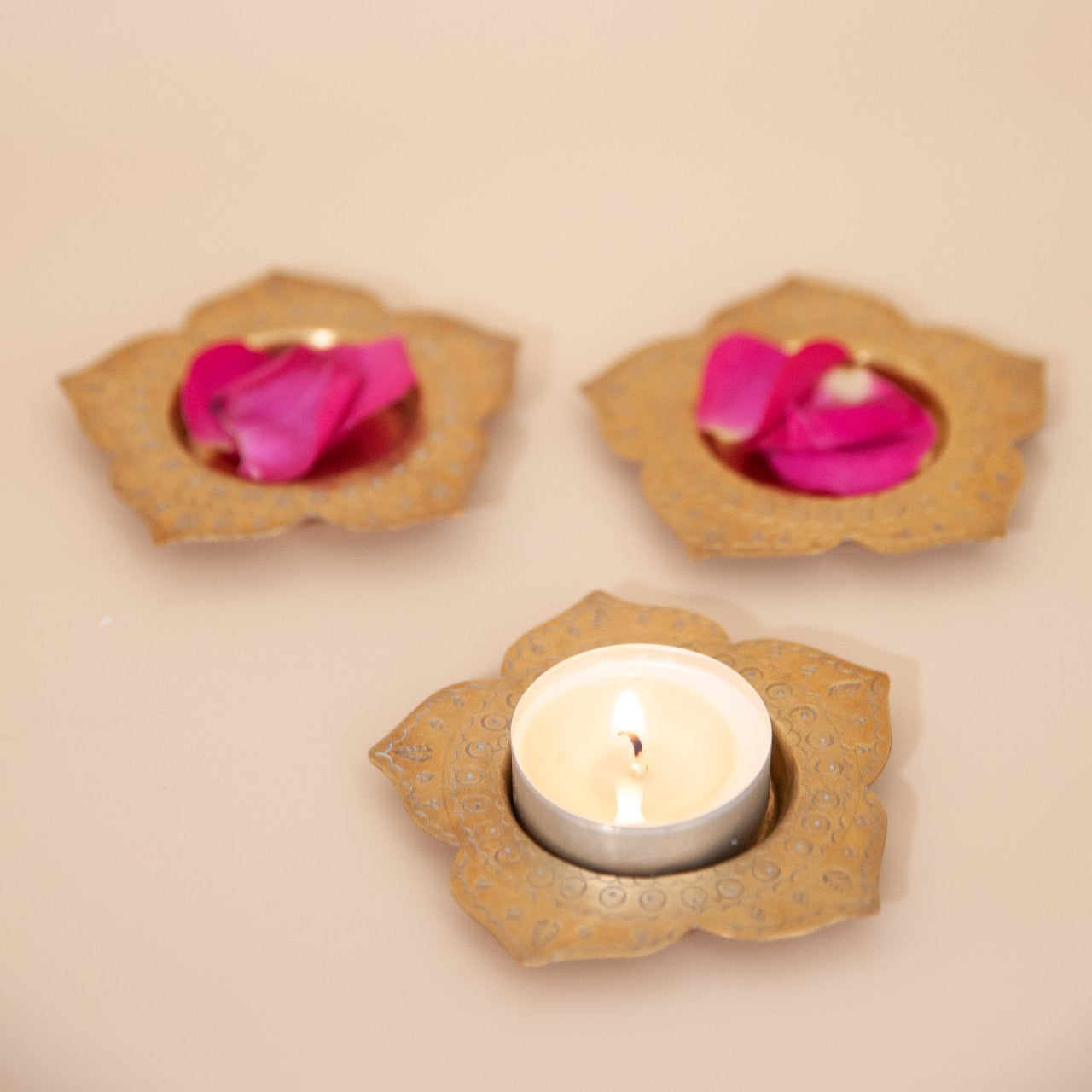 Three decorative candle holders with pink flowers on a beige background