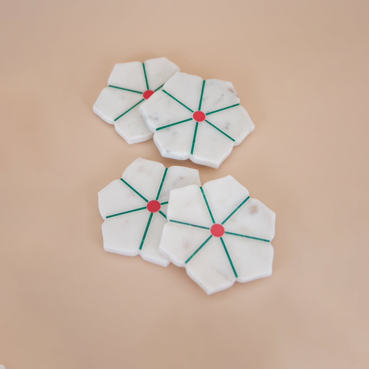White marble coaster with red centers and green lines on a beige background