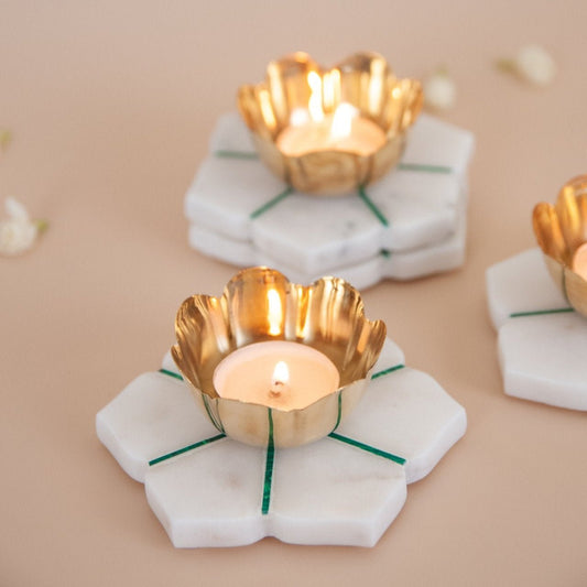 Gold candle holders on white marble coasters with a beige background