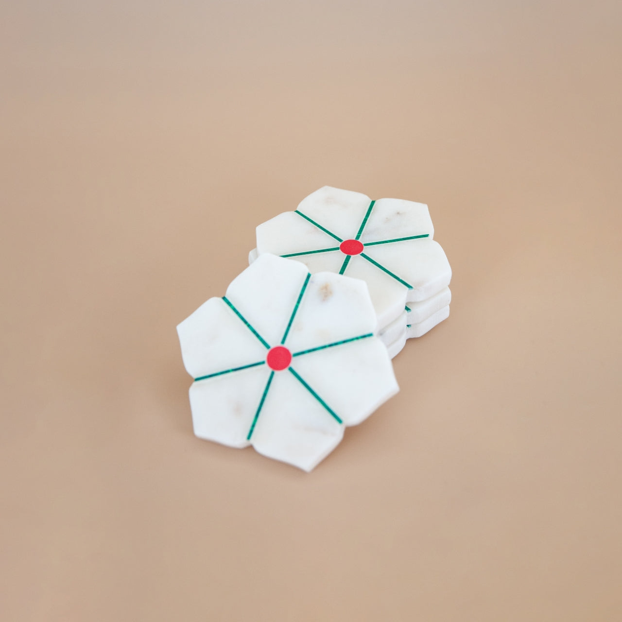 White marble coaster with red centers and green lines on a beige background