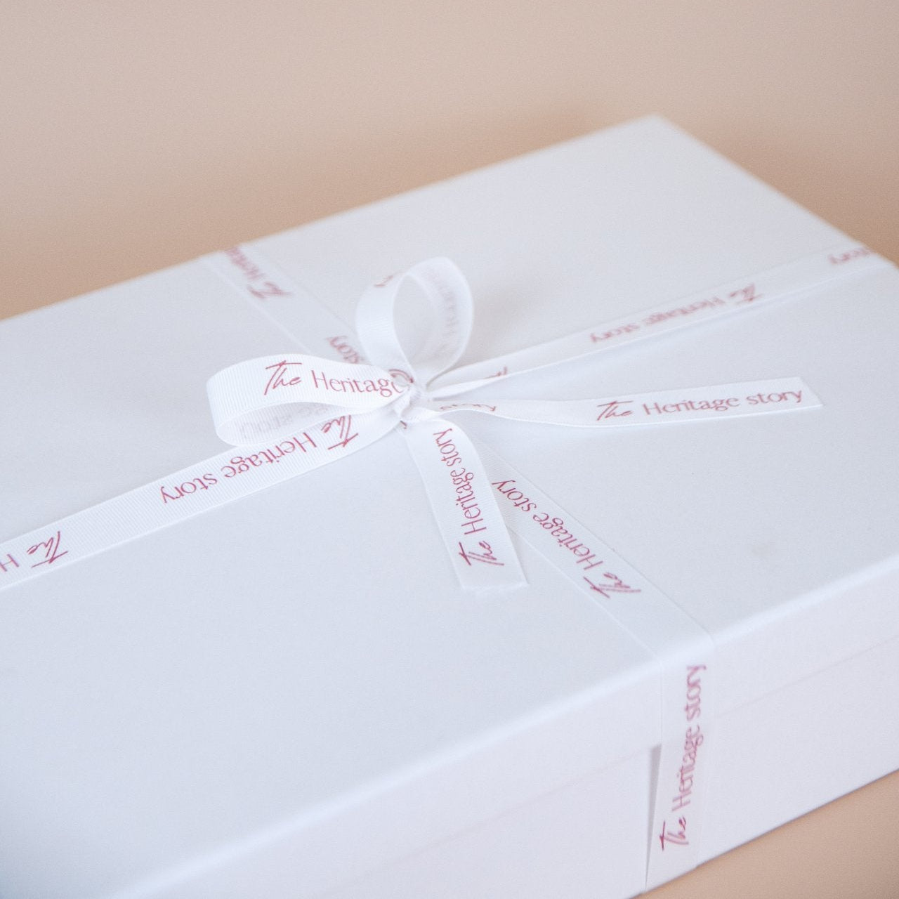 White gift box with a ribbon on a beige background