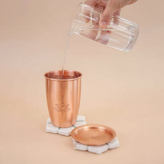 Copper tumbler with a lid being filled with liquid on a beige background