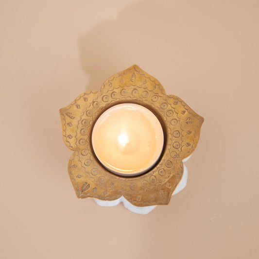 Decorative brass tealight holders with intricate design on a beige wall.