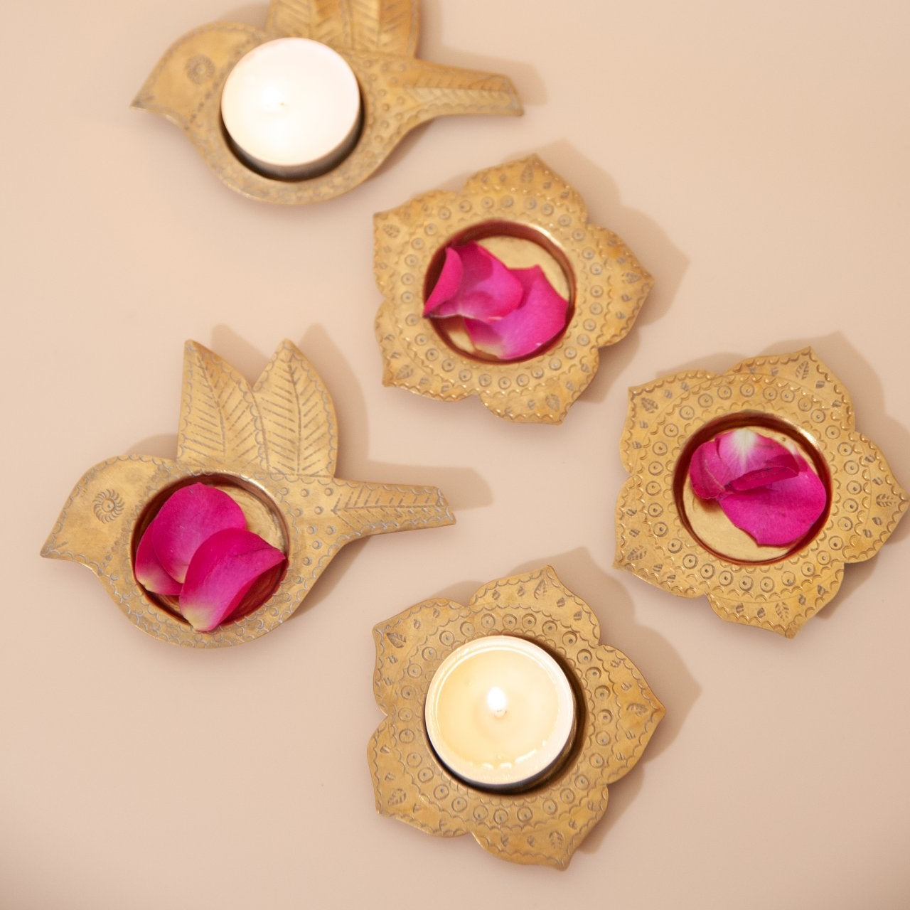 Decorative brass candle holders with pink flowers on a beige background