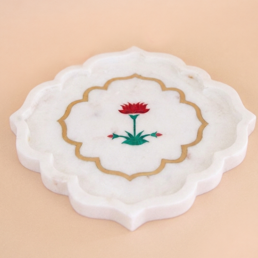 Decorative marble platter with floral and brass inlay design on a beige background