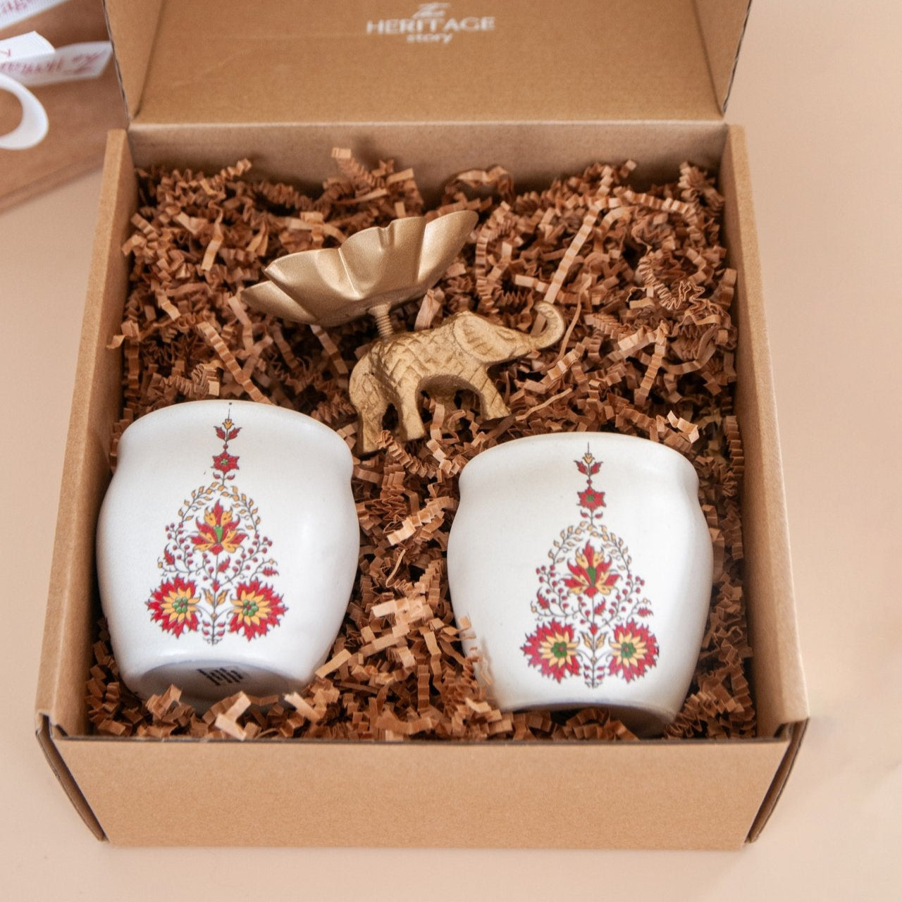 Two ceramic kulhads with floral designs and an elephant tealight holder in a box with 'Heritage' branding.