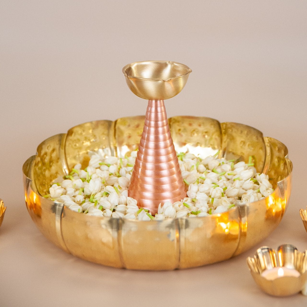 Decorative brass bowl with flowers and a smaller brass container on a beige background