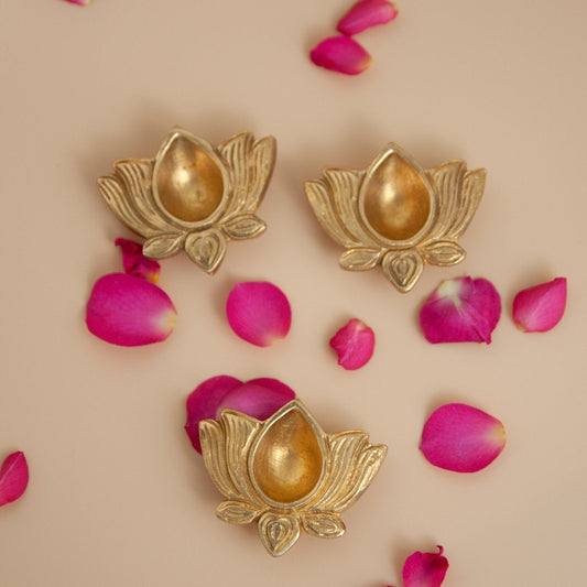 Brass lotus-shaped earrings with pink petals on a beige background