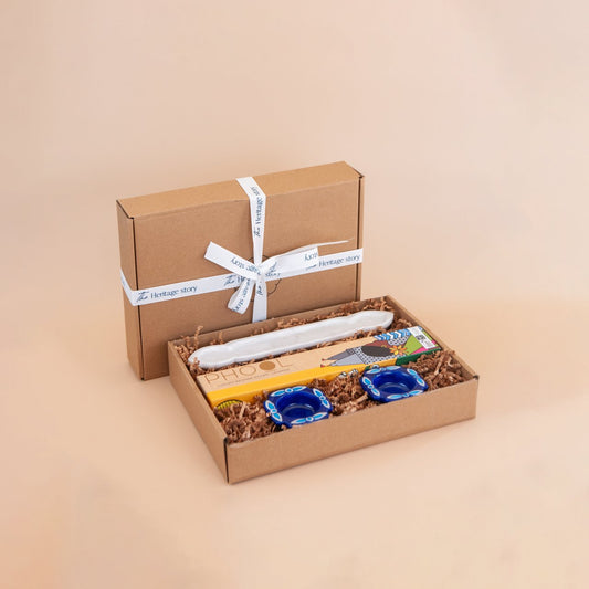 Gift box with a marble incense holder, artisnal incense sticks and blue pottery ealight holders on a beige background