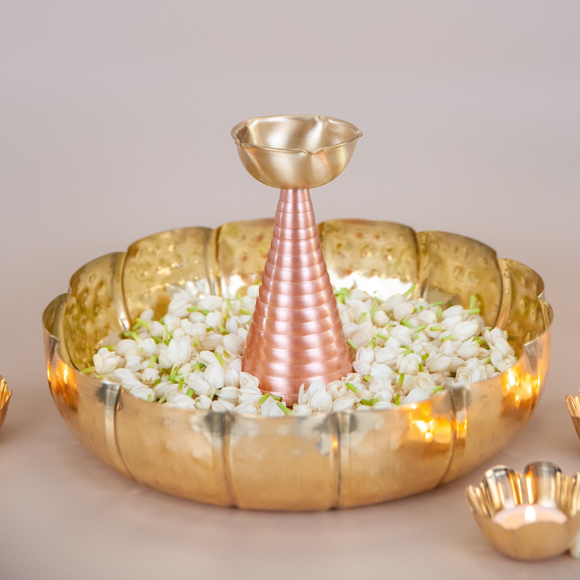 Decorative gold bowl with a  brass candle holder on a neutral background
