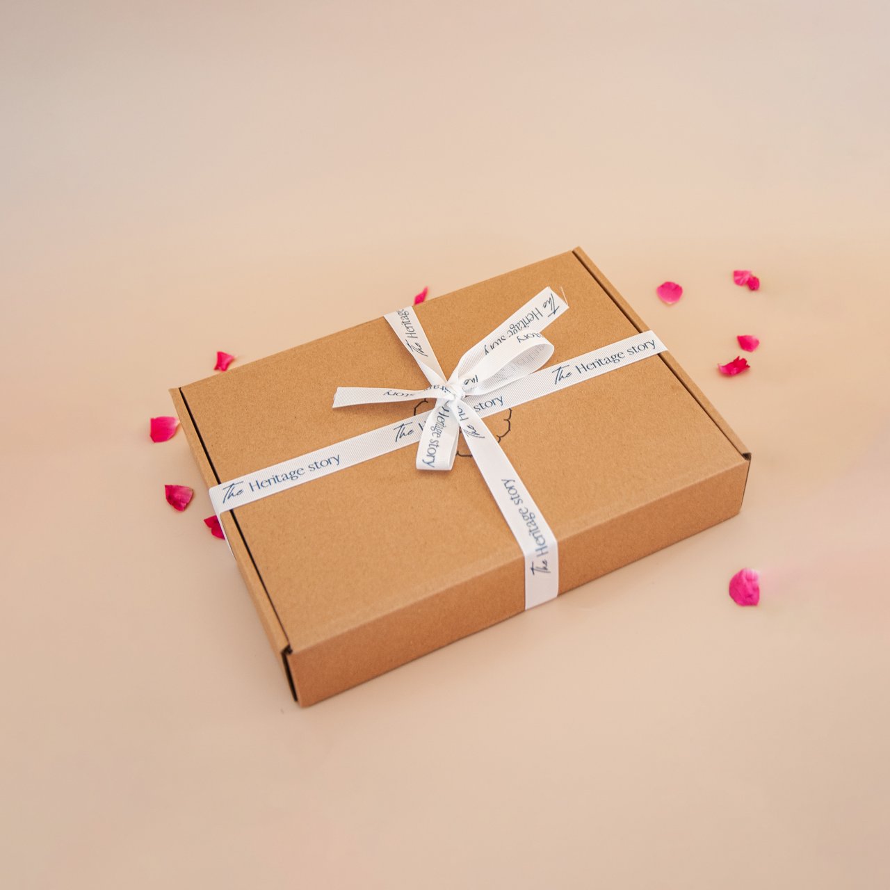 Brown gift box with white ribbon and 'The Heritage Story' label on a beige background
